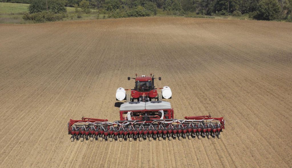 tractor planting seeds in large arable field